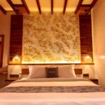Close-up of the plush king-size bed and stunning illuminated textured gold headboard in the second-floor Deluxe Double room at Kuda Putih Pandawa Bali.
