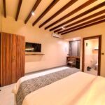 Spacious interior of the second-floor Deluxe Double room featuring a dedicated wooden desk, mini-fridge, and comfortable bedding at Kuda Putih Pandawa South Kuta.
