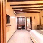 View from the entrance of the second-floor Deluxe Double room showcasing the aesthetic wooden partition, flat-screen TV, and modern layout at Kuda Putih Pandawa guesthouse.