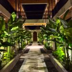 A tropical garden pathway illuminated by warm floor lights leading to a wooden door at the premium Kuda Putih Pandawa accommodation near Pandawa Beach.