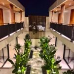 A symmetrical top-down view of the tropical plant pathway and wooden architecture at Kuda Putih Pandawa Bali at night.