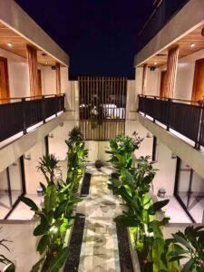 A symmetrical top-down view of the tropical plant pathway and wooden architecture at Kuda Putih Pandawa Bali at night.