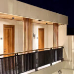 Architectural details of wooden pillars and guest room doors on the second-floor balcony of Kuda Putih Pandawa Bali with elegant night lighting.