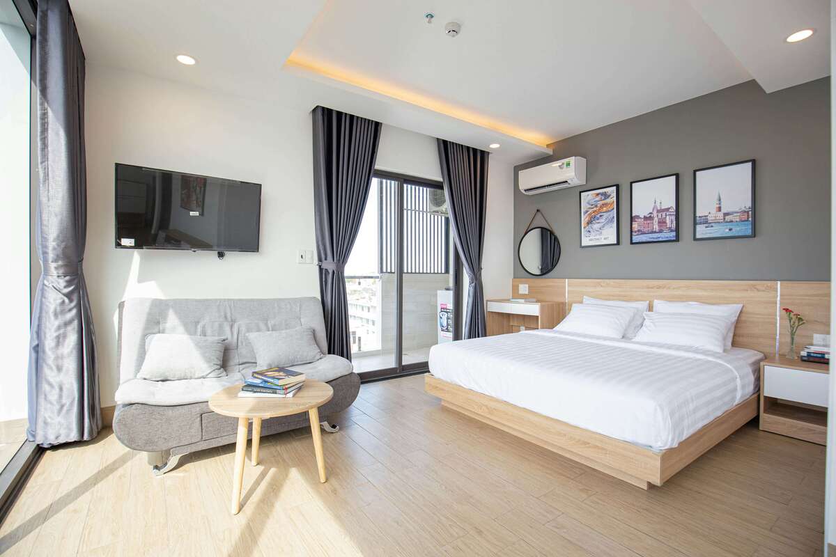 Modern interior design of the Elevated Classic Room with a double bed, sofa seating area, and elegant decor at Kuda Putih Pandawa Guesthouse.