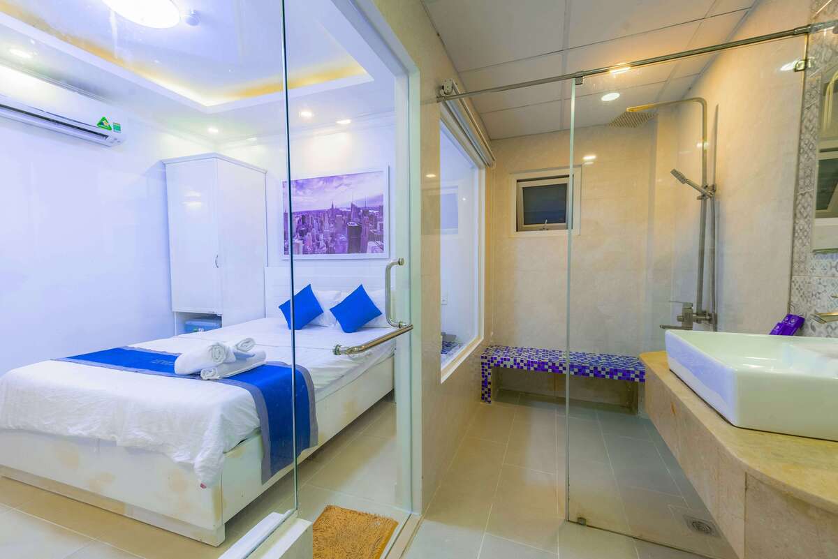 A bedroom directly connected to a modern clear glass-partitioned bathroom, complete with shower facilities at Kuda Putih Pandawa Bali.