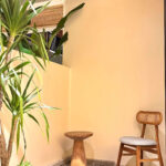 A tranquil private garden patio featuring a wooden chair, side table, and tropical plants outside the Deluxe Double room at Kuda Putih Pandawa South Kuta.