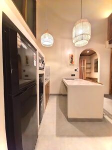Detailed view of the suite amenities including a full-size refrigerator, microwave, and water dispenser in the kitchenette at Kuda Putih Pandawa guesthouse.